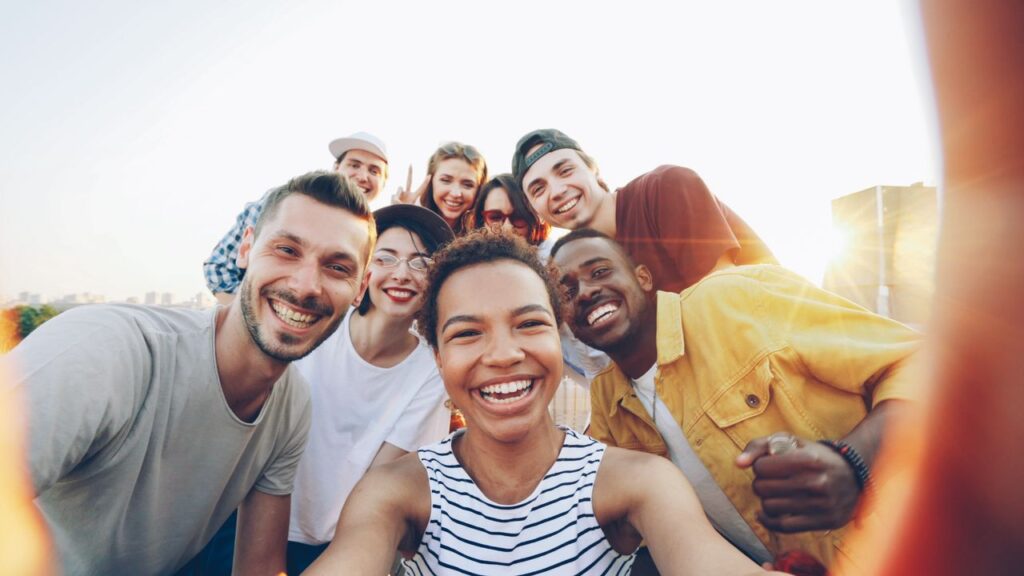 A diverse group of friends taking a joyful selfie outdoors during sunset.